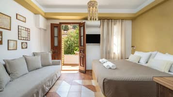 A bedroom with a sofa, a bed, a TV, and a door leading to a balcony.