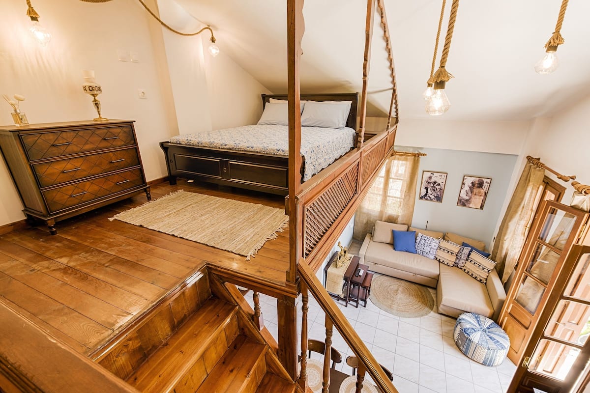 Une chambre avec un escalier en bois, un lit, une commode et un canapé.