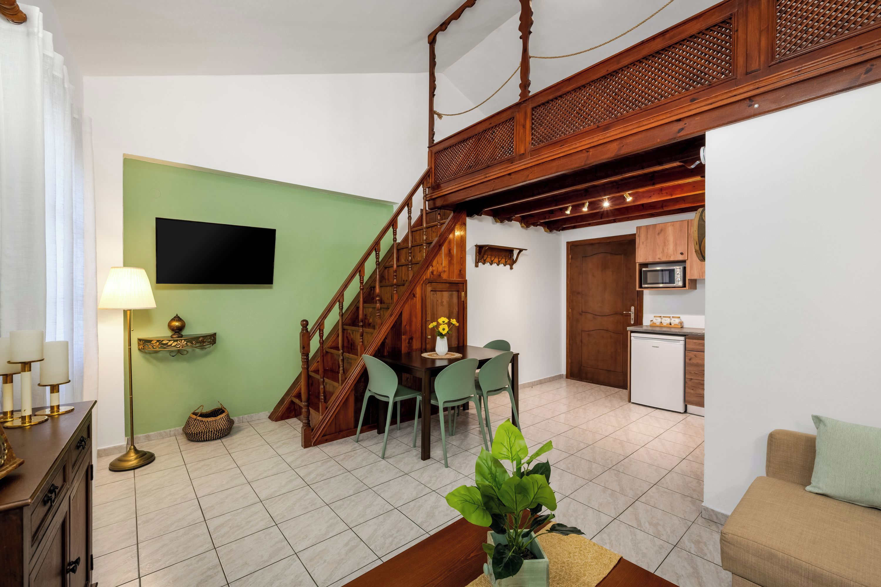 A living room with a staircase, a dining area, and a kitchen.