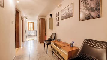 A hallway with a wooden desk, a leather sofa, and framed pictures on the wall.