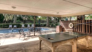 A covered outdoor area with a ping pong table, lounge chairs, and a swimming pool. - Access to Community Pool & 1 Block to the Beach! (Saint Simons Island)