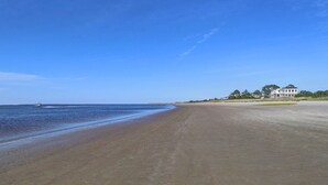 A wide sandy beach with a large house in the background. - Heated Pool Access | 5*Clean | Flex Cancelation (Tybee Island)