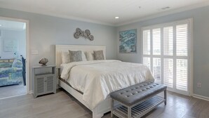 A bedroom with a bed, bench, and artwork. - Heated Pool Access | 5*Clean | Flex Cancelation (Tybee Island)