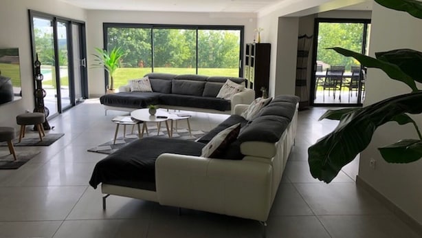 Een moderne woonkamer met een modulaire bank, een salontafel en een eethoek met stoelen.