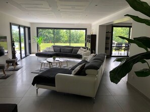 Uma sala de estar moderna com um sofá seccional, uma mesa de centro e um espaço de jantar com cadeiras.