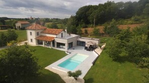 Uma casa moderna com piscina, um pátio e um jardim.