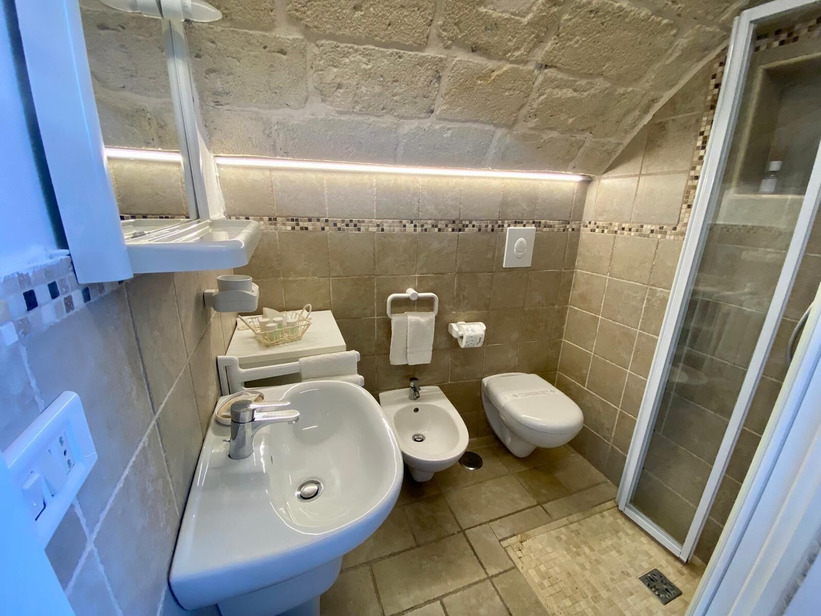 Une petite salle de bain moderne équipée d’un lavabo, d’un bidet, de toilettes et d’une douche.