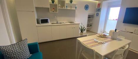A compact living space with a kitchenette, dining area, and a sofa.