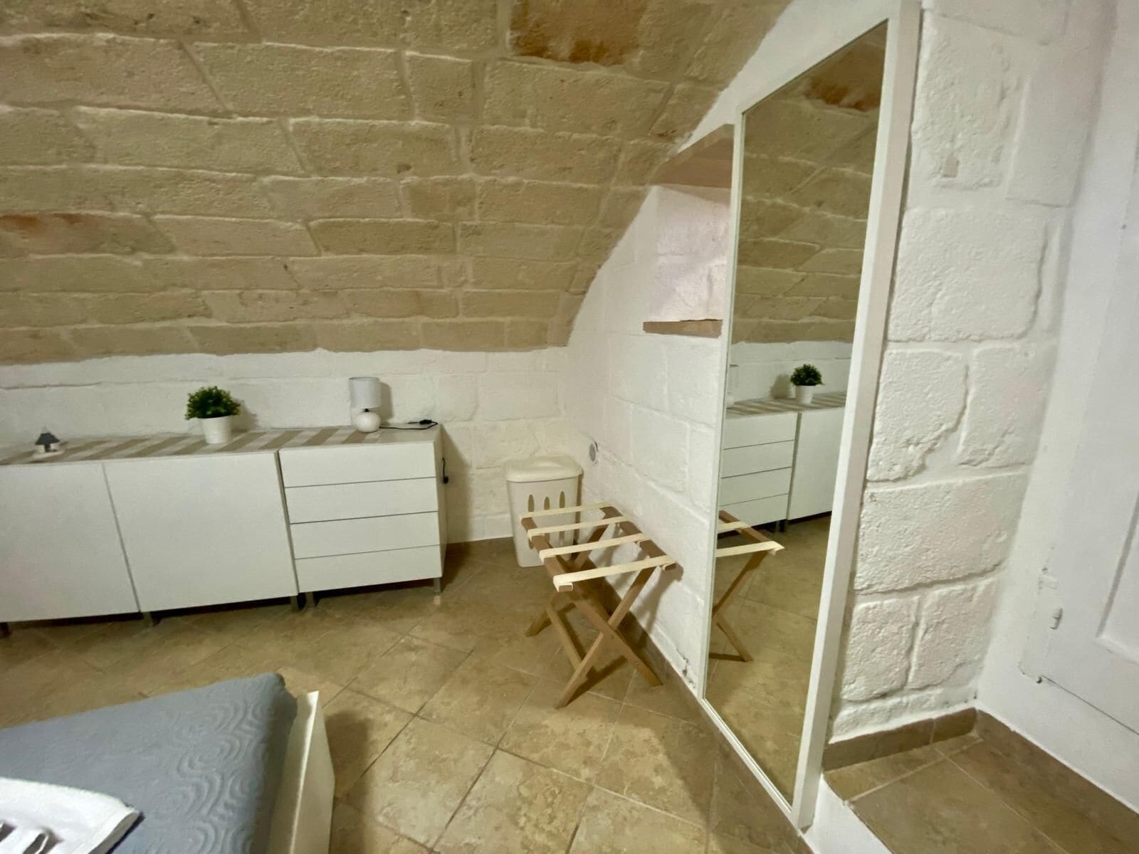 Habitación pequeña con un tocador blanco, una mesita y una silla. Un espejo refleja parte de la habitación.