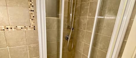 A bathroom with a toilet, a shower with a glass door, and tiled walls.