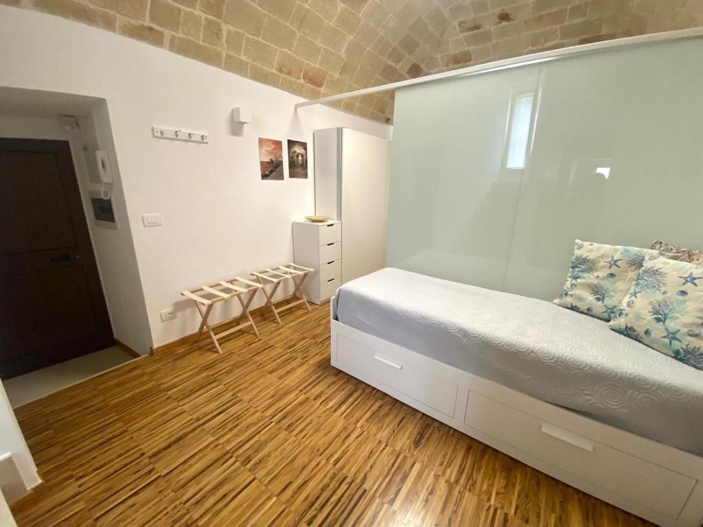 Ein Schlafzimmer mit Holzboden, einem Bett mit weißem Kopfteil, einem kleinen Tisch und einem Kleiderschrank.