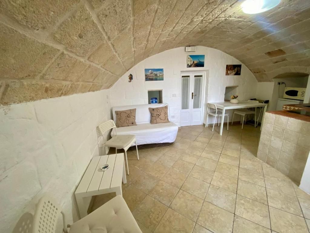 Une pièce chaleureuse avec un plafond en pierre, un canapé blanc agrémenté de coussins, une petite table et une chaise blanche.