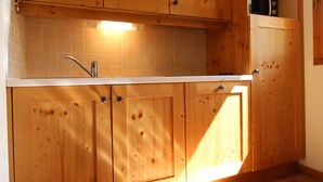 A kitchen with wooden cabinets, a white countertop, and a tiled backsplash.