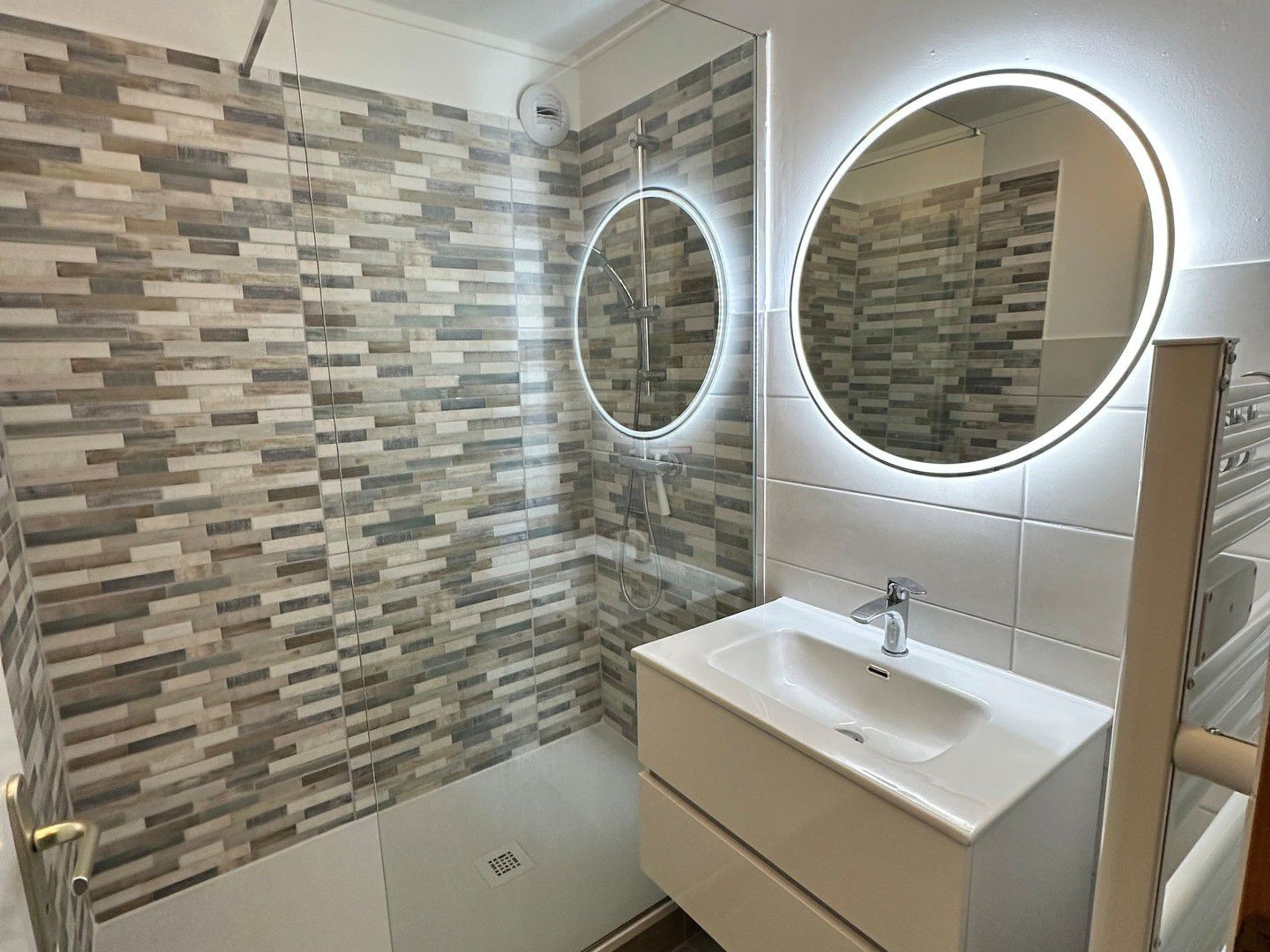 A bathroom with a shower, a sink, and two mirrors.