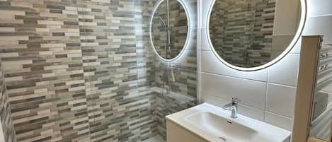 A bathroom with a shower, a sink, and two mirrors.