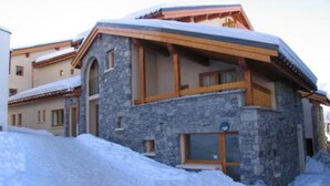 Un bâtiment en pierre doté d’un balcon en bois et d’un toit recouvert de neige.
