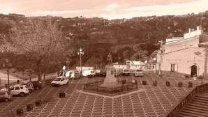 A parking lot with a statue in the center, surrounded by buildings and trees. - B&B Torre Castellina (Piazza Armerina)