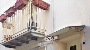 A building with a white facade, a balcony with hanging flower pots, and a door marked with the number 48. - B&B Torre Castellina (Piazza Armerina)