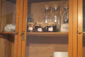 A wooden cabinet with glass doors containing bottles labeled with names and prices. - B&B Torre Castellina (Piazza Armerina)