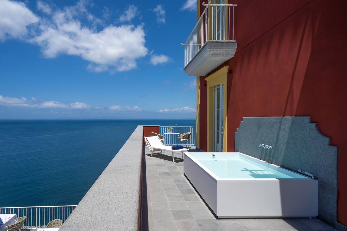 Un balcon avec une piscine, des chaises longues et une vue sur l’océan.