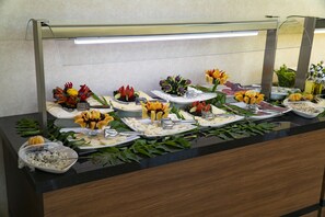 A buffet setup with various food items and fresh flowers. - Angel's Park Hotel (Denizli)