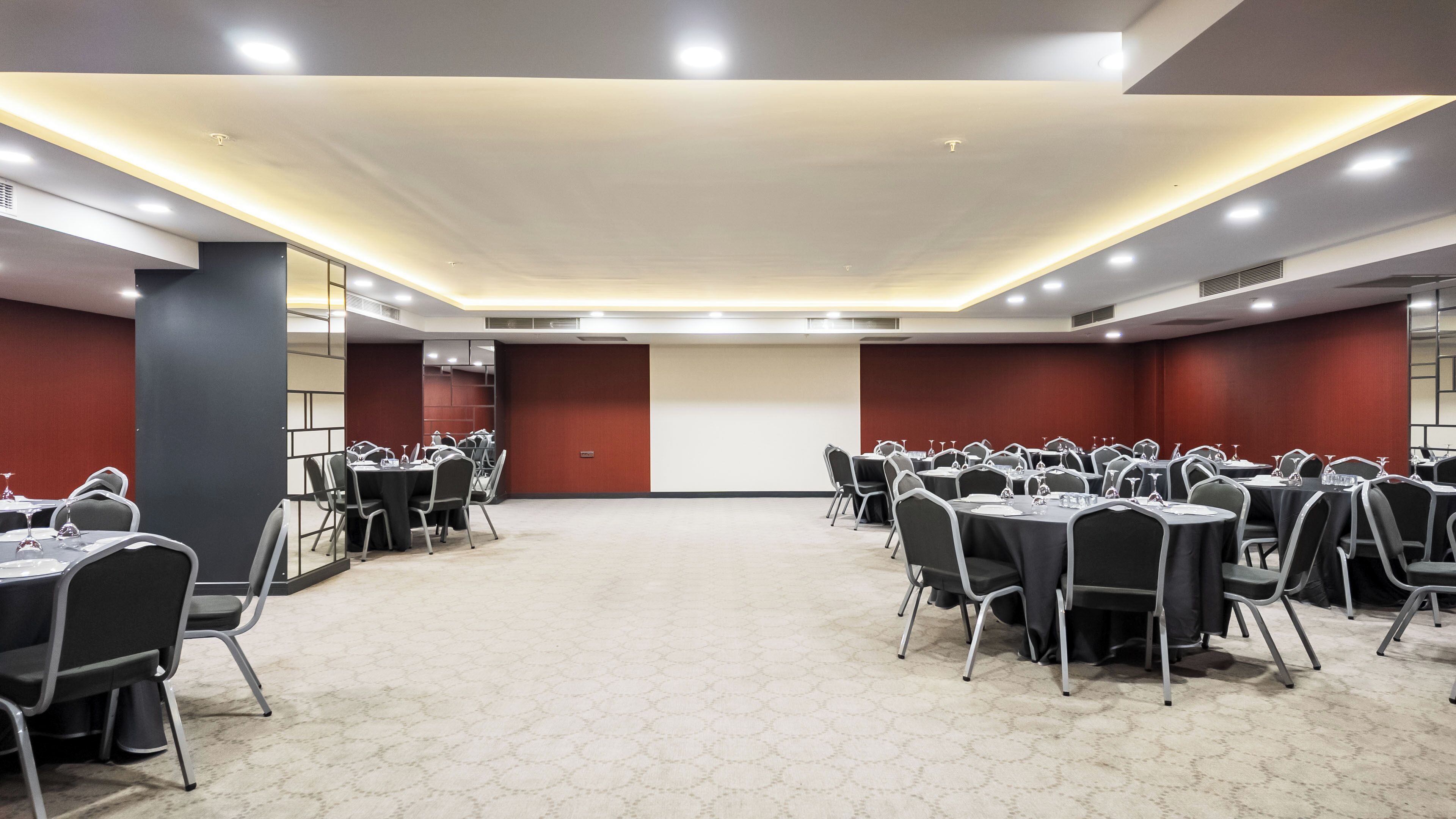 Un salón de conferencias con varias mesas y sillas, equipado con tarjetas de identificación y vasos de agua.