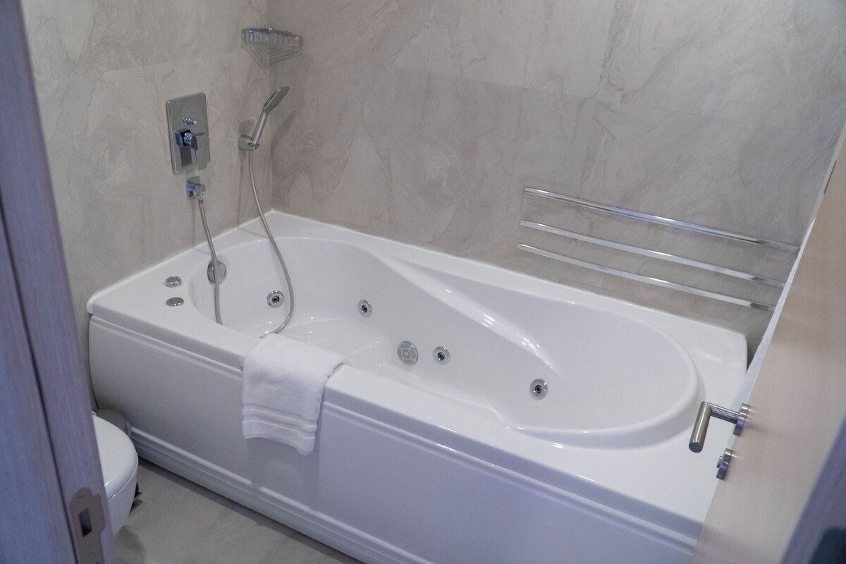 A modern bathroom with a freestanding bathtub, a showerhead, and a toilet.