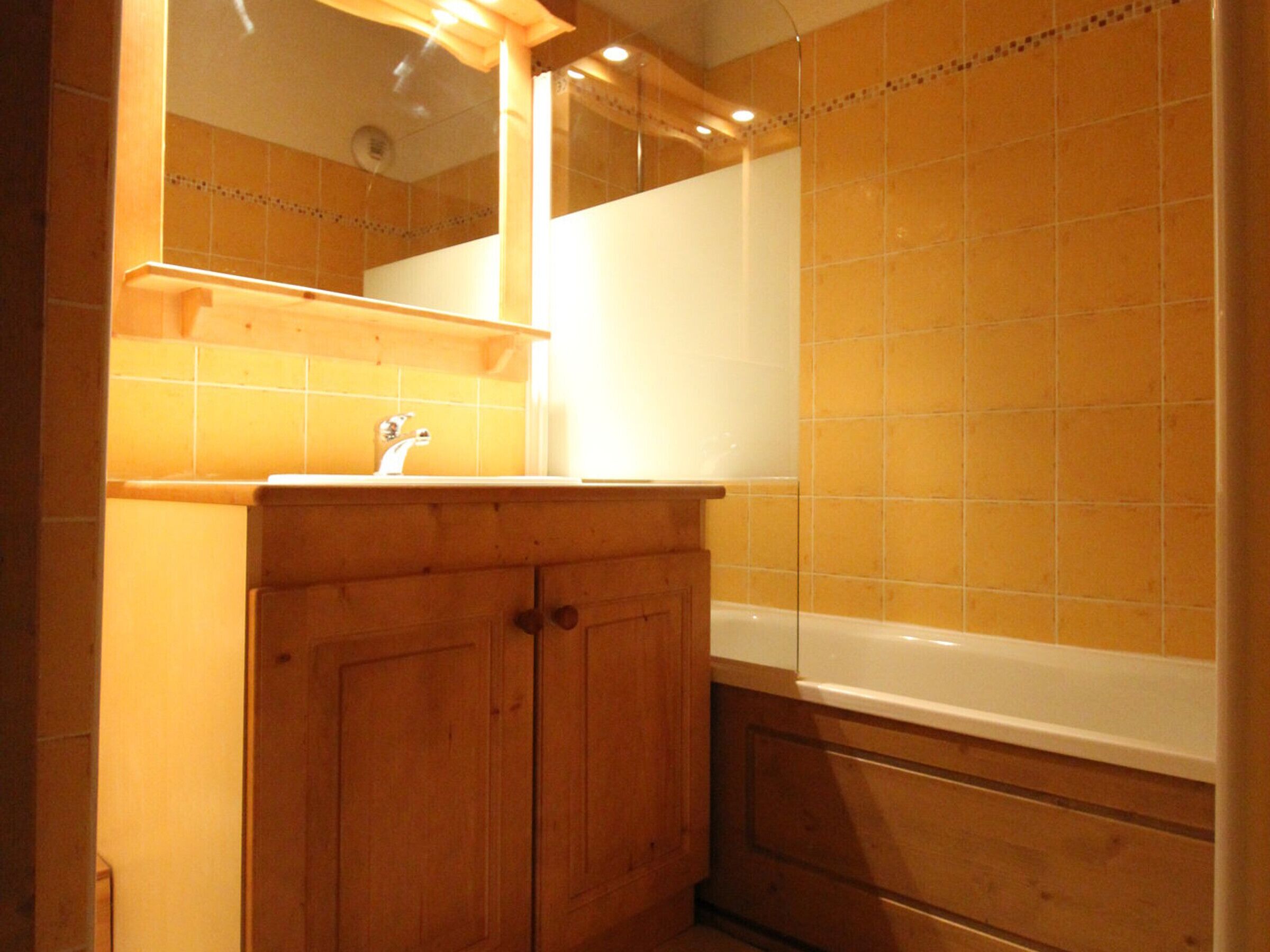 Un bany amb armaris de fusta, un lavabo i una banyera.