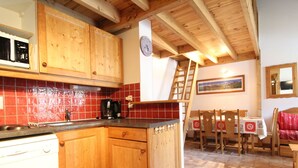 Une cuisine dotée de meubles en bois, d’une machine à café et d’un coin repas avec une table et des chaises.