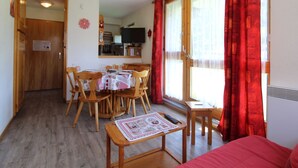 Un espacio habitable compacto con comedor, kitchenette y una zona de estar acogedora.