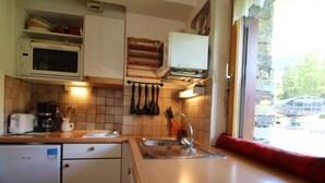 Una cocina compacta con microondas, cafetera y lavabo.