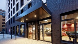 Un edifici modern amb façana de vidre i una entrada gran i il·luminada.