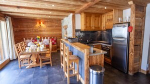 Un intérieur en bois comprenant un coin repas, une cuisine et une poubelle.