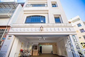 A hotel entrance with a modern design, featuring a large arched window, a covered entrance, and a staircase leading to the upper floors. - J.S 23 Kids Homestay (Kaohsiung)