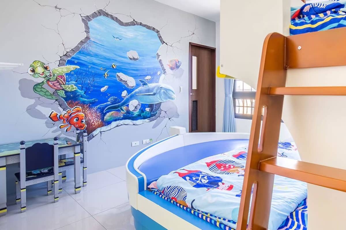 A child's bedroom with a bunk bed, a desk, and a wall mural of an underwater scene.