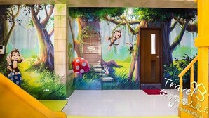 A mural with a forest scene, a door, and a yellow staircase. - J.S 23 Kids Homestay (Kaohsiung)