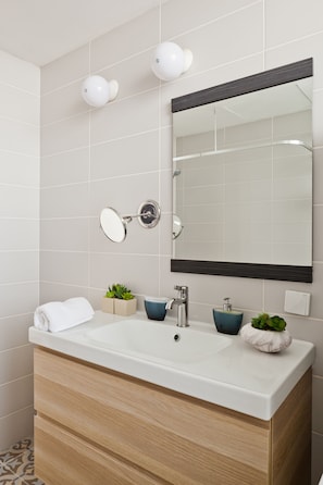 A modern bathroom with a large mirror, a white sink, and a wooden vanity. - Superior & Spacious Duplex in the Kerem (Tel Aviv)