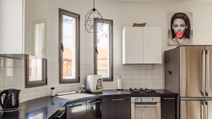Ett modernt kök med en svart bänkskiva, vitvaror i rostfritt stål och vita skåp.