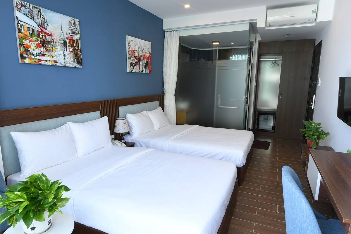 Een hotelkamer met twee bedden, een televisie, een plant en kunstwerken aan de muur.