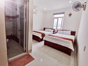 A hotel room with two beds, a shower, and a window.