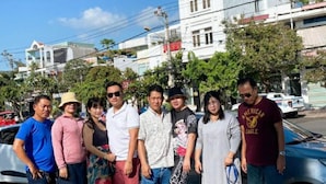 A group of people standing in front of a building with a sign that reads "AMY HOTEL".