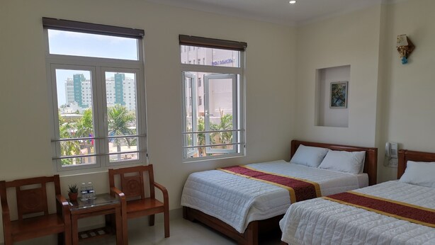 A hotel room with two beds, a small table, and chairs.