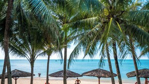 A beach with palm trees, beach chairs, and umbrellas. - L'Azure Resort and Spa (Phu Quoc)