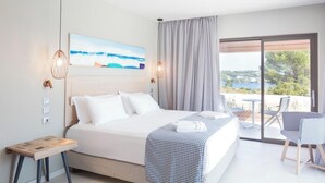 Camera d'albergo moderna con un letto grande, vista sul mare e un balcone con mobili da esterno.