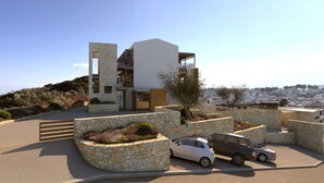 Un edificio moderno con facciata in pietra, diversi balconi e un'area di parcheggio con auto.