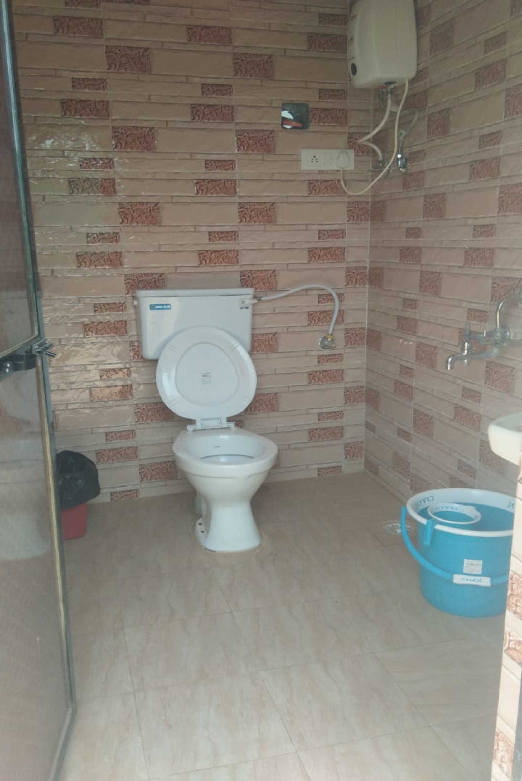 A small bathroom with a toilet, a sink, and a blue bucket.