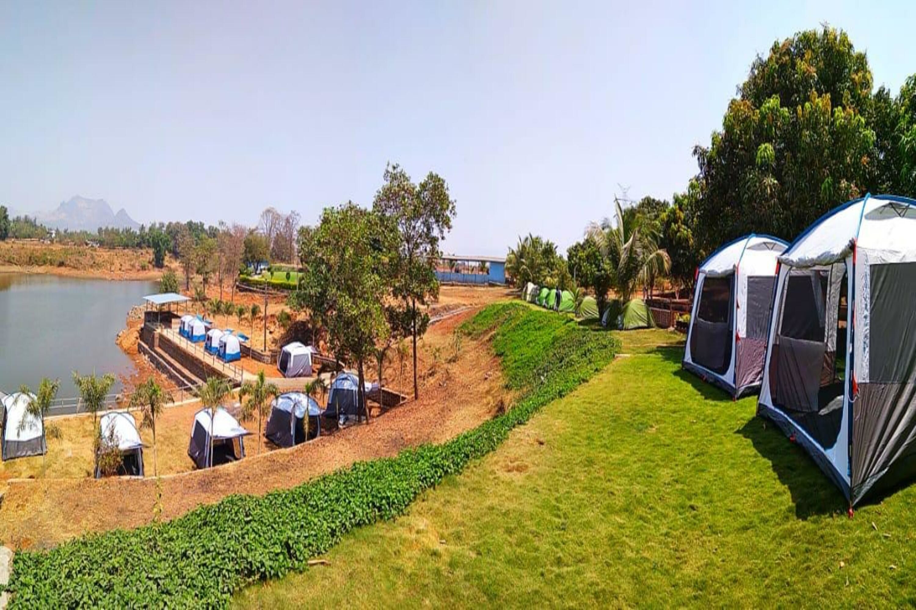 Un camping con tiendas de campaña y un lago.