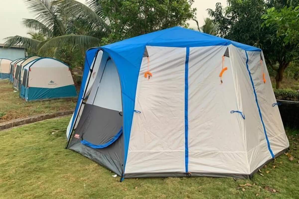 Une tente de camping aux couleurs bleu et gris, installée sur une pelouse, avec des arbres en arrière-plan.