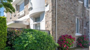 Un edificio de piedra con un camino empedrado, setos cuidados y plantas con flores.
