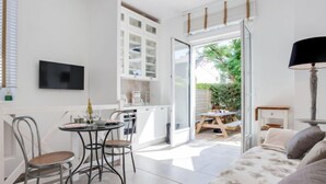 Una cocina luminosa y moderna con armarios blancos, un comedor con mesa y sillas, y una sala de estar acogedora con un sofá.